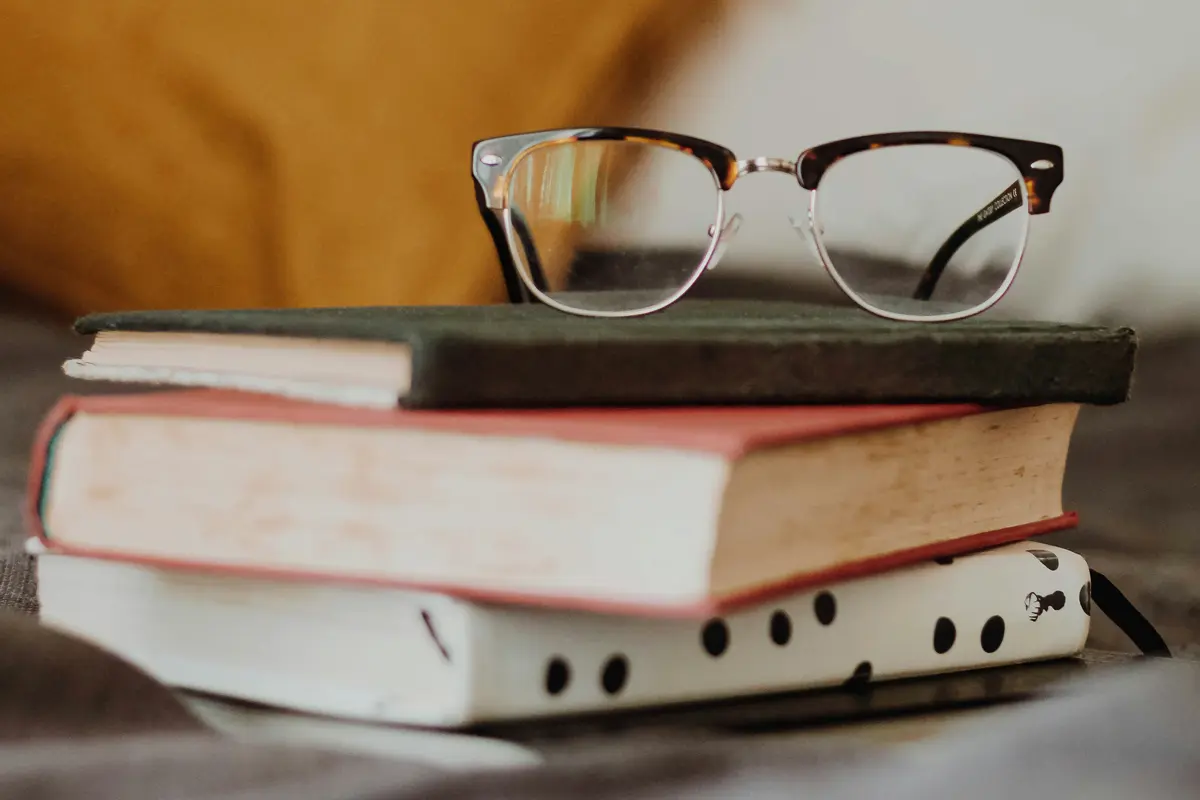 Books and reading glasses on a bedside table